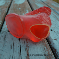 Photo shows a latex condom stretched over the whole red jelly dildo, including base and balls