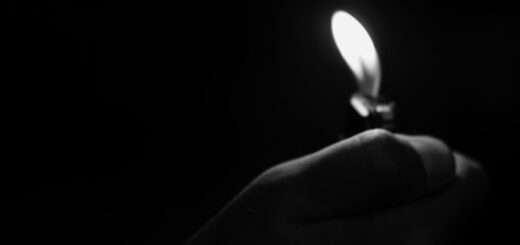 A photo that is almost entirely black - you can see the flame from a lighter and a small bit of the hand holding the lighter.