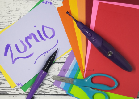 Zumio Classic Review - Zumio shown on top of multi-colored papers with craft scissors and a paint marker